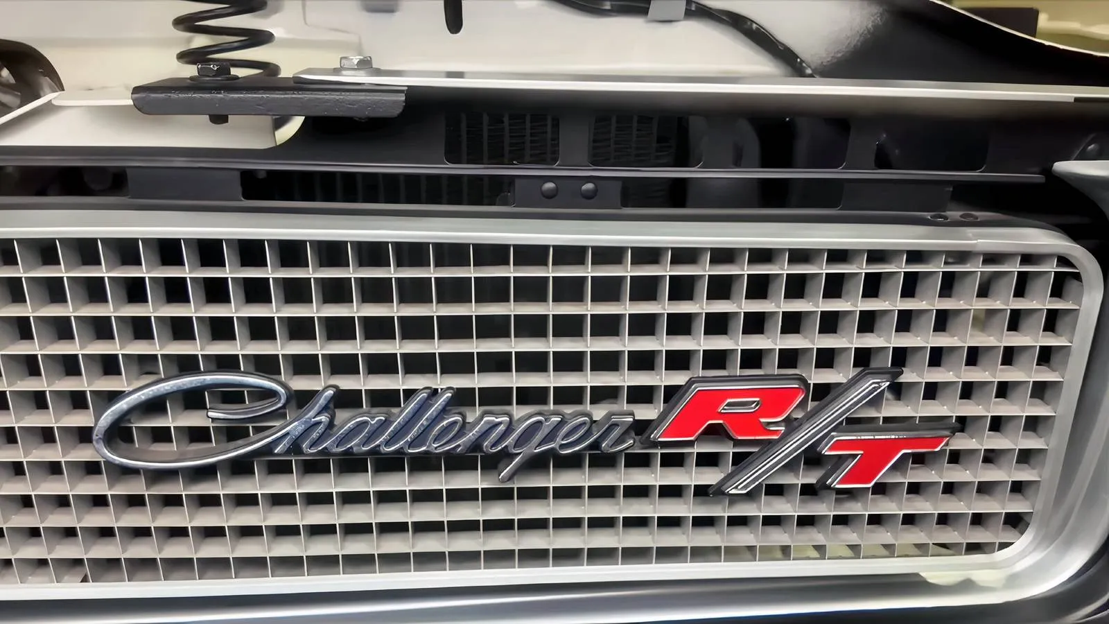 A white 1970 Dodge Challenger with its hood open, showcasing the newly installed original 440 Magnum engine in a well-equipped garage.