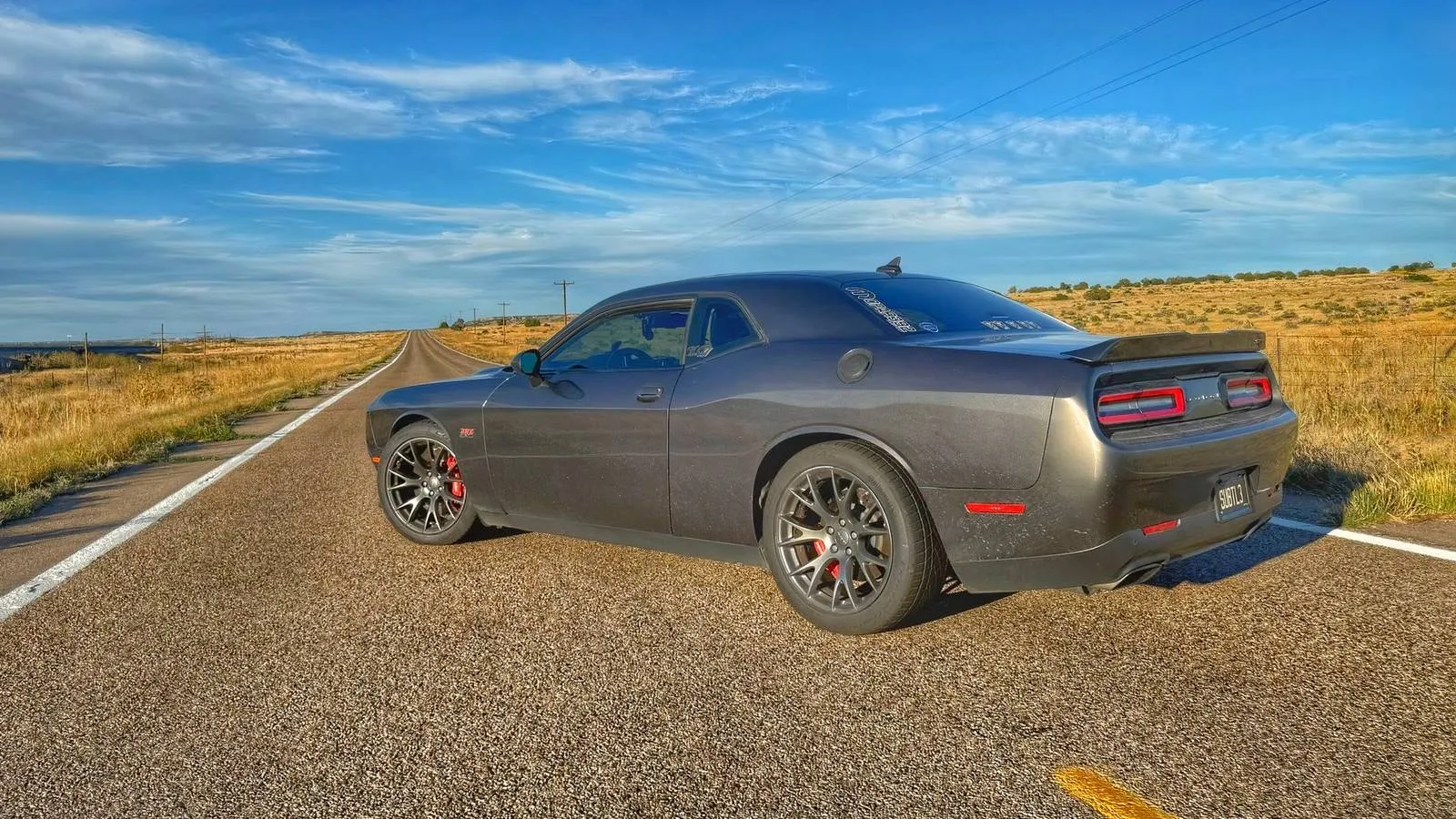 A well-worn white Dodge Challenger SRT 392, its body hinting at over a decade of daily driving
