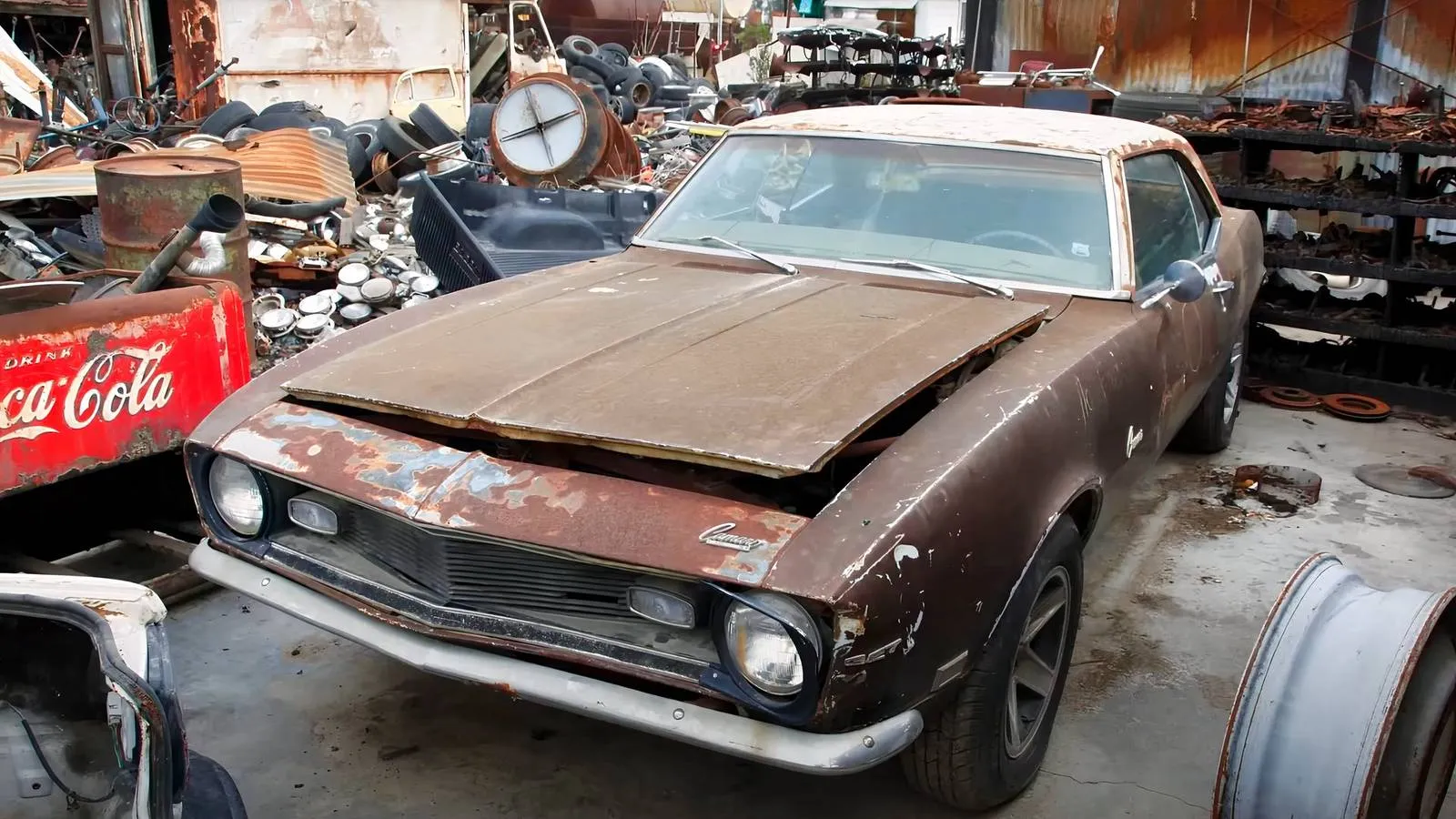 A faded 1968 Camaro resting among desert brush, its patina telling tales of street races long past