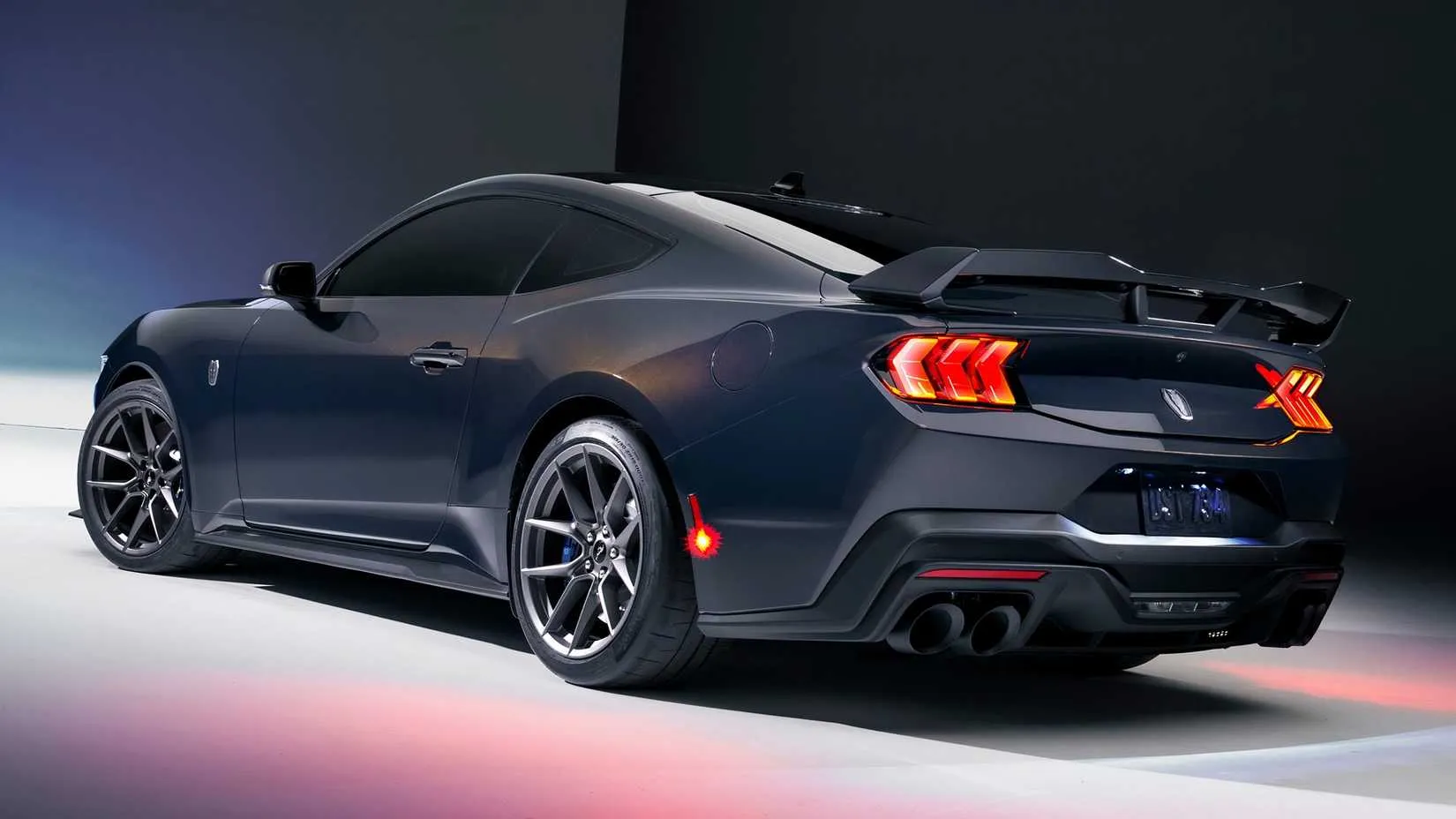 Rear 3/4 view of a 2024 Ford Mustang GT, highlighting taillights and exhaust