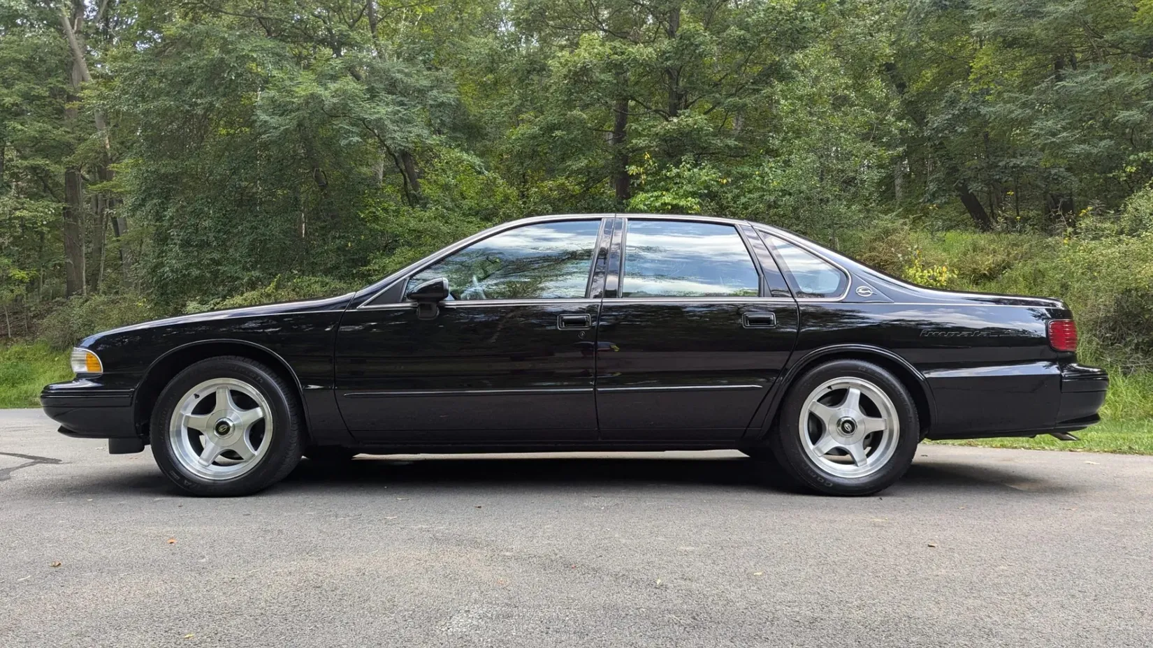 A pristine black Impala SS cruising an urban background