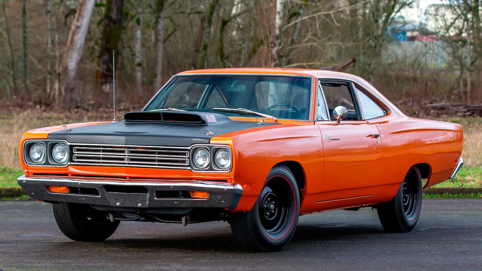 An orange 1969 Plymouth Roadrunner 440 Six Pack parked on grass