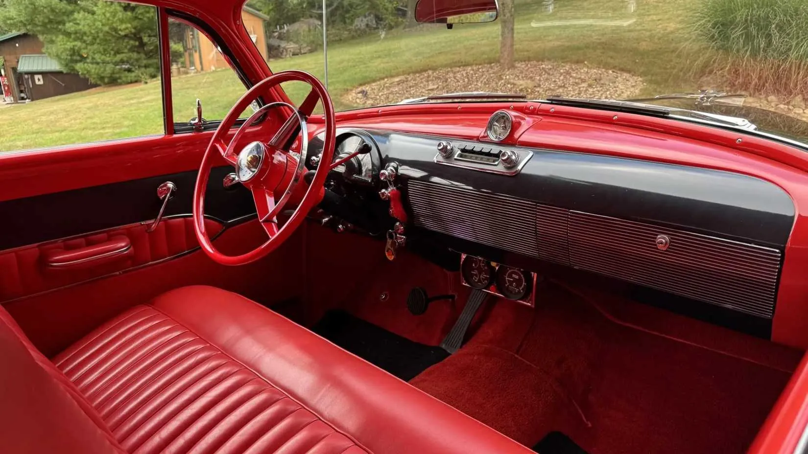 Red interior of the 1950 Oldsmobile with aftermarket tachometer and auxiliary gauges