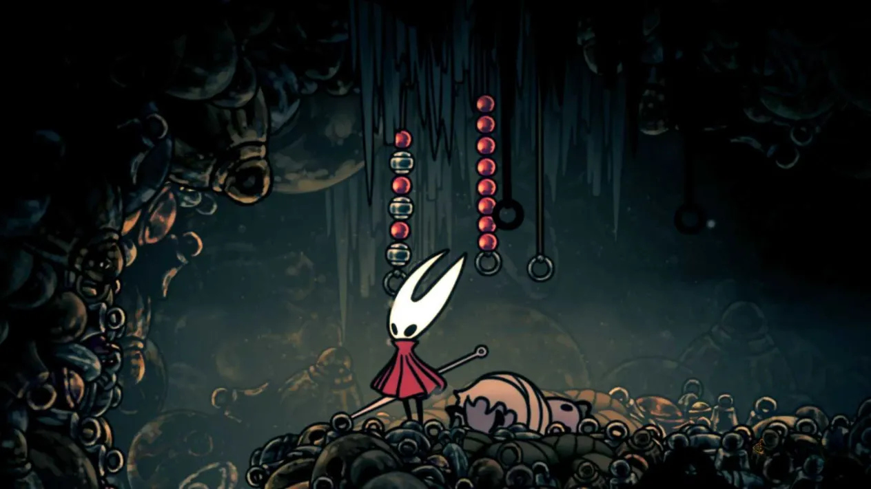 Hornet standing near hanging rosary beads in Silksong